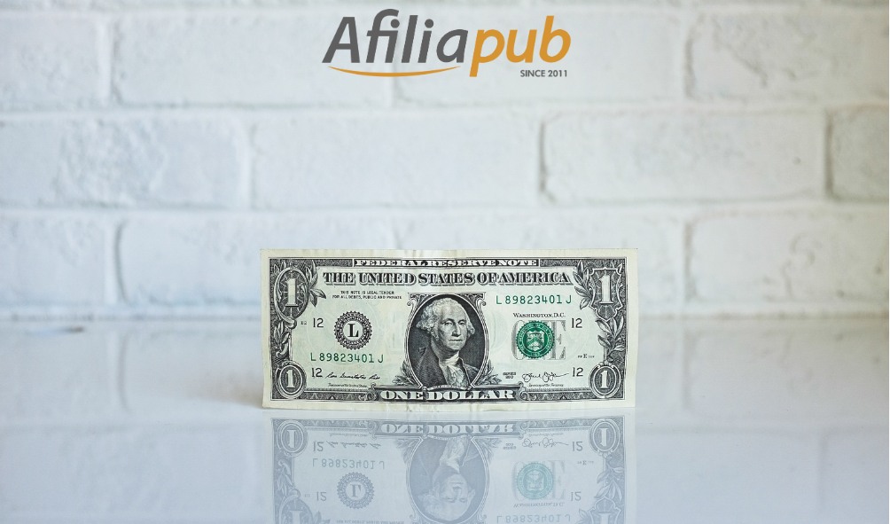 Nota de dólar em fundo branco com logo de Afiliapub acima dela.